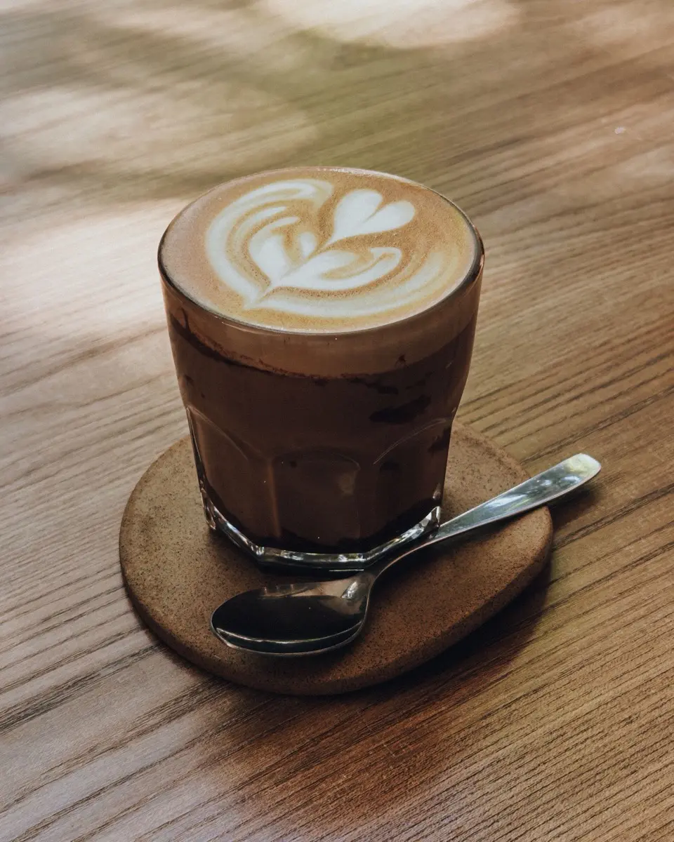A flat white coffee with latte art on a wooden cafe table