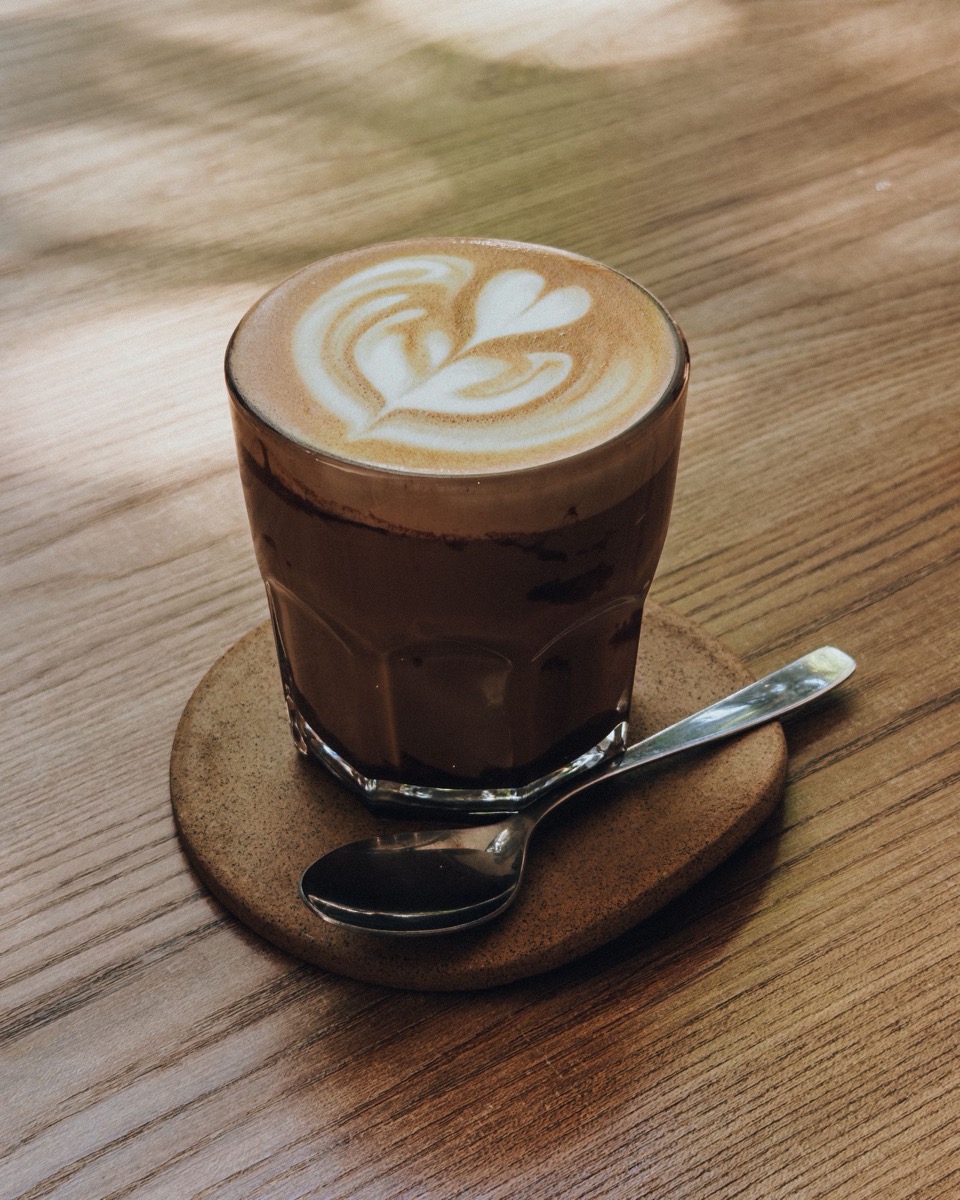 A flat white coffee with latte art on a wooden cafe table